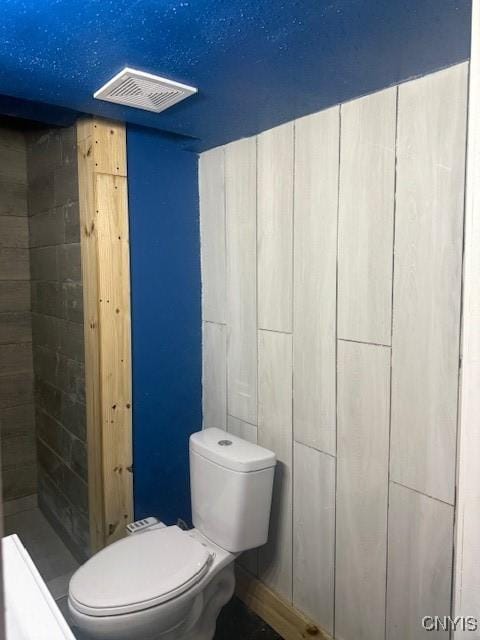 bathroom featuring toilet, visible vents, and tiled shower