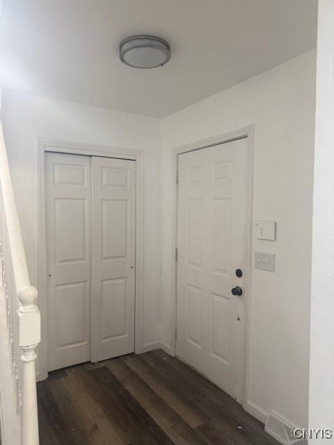 interior space with dark wood-type flooring, visible vents, and baseboards