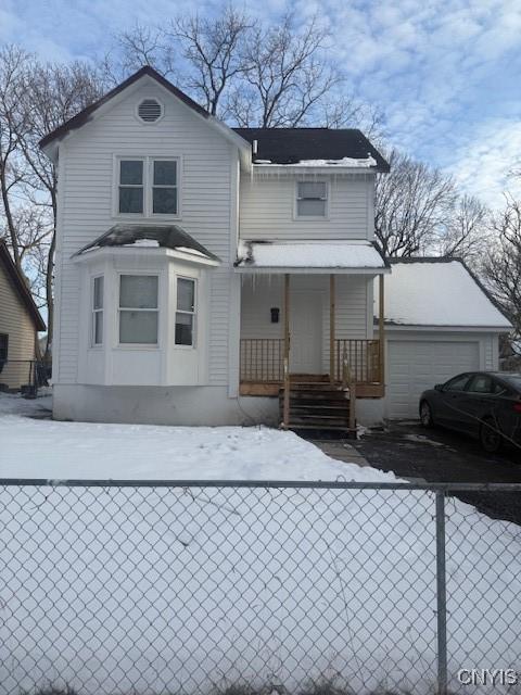 view of front of property with driveway, a fenced front yard, a porch, and an attached garage