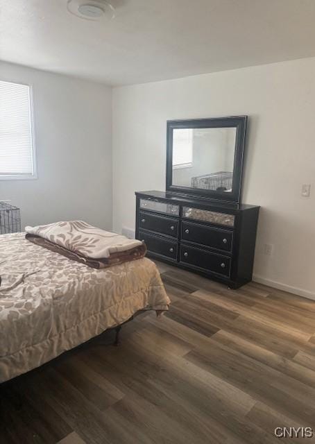 bedroom with dark wood-type flooring and baseboards