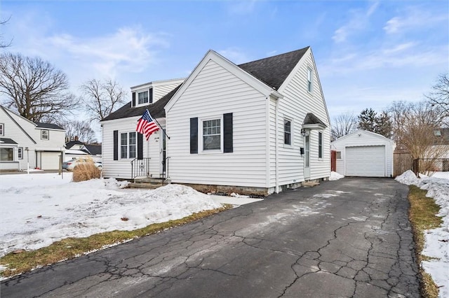 view of front of home with roof with shingles, a detached garage, aphalt driveway, and an outbuilding