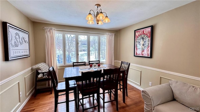 dining room with a chandelier, a wainscoted wall, a decorative wall, and hardwood / wood-style floors