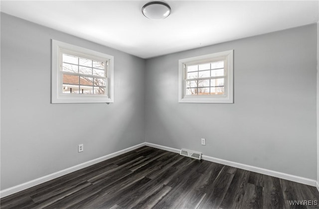 unfurnished room with a healthy amount of sunlight, visible vents, and baseboards