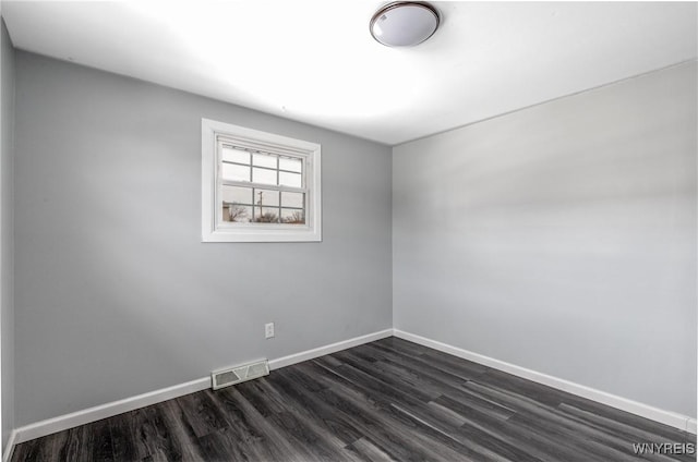 empty room featuring visible vents, dark wood finished floors, and baseboards