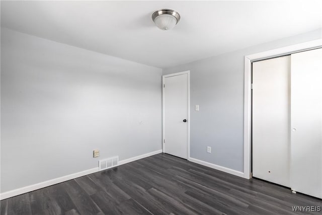 unfurnished bedroom with baseboards, a closet, visible vents, and dark wood-style flooring