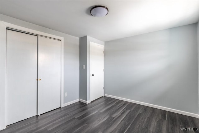 unfurnished bedroom with baseboards, dark wood finished floors, and a closet