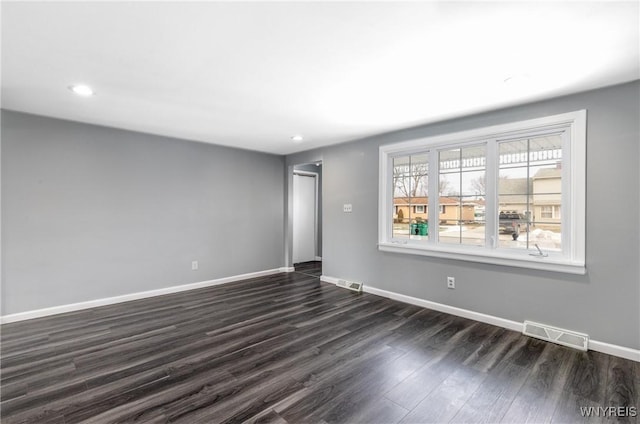 empty room featuring dark wood-style flooring, recessed lighting, visible vents, and baseboards