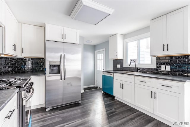 kitchen with appliances with stainless steel finishes, dark countertops, dark wood-style flooring, and white cabinets