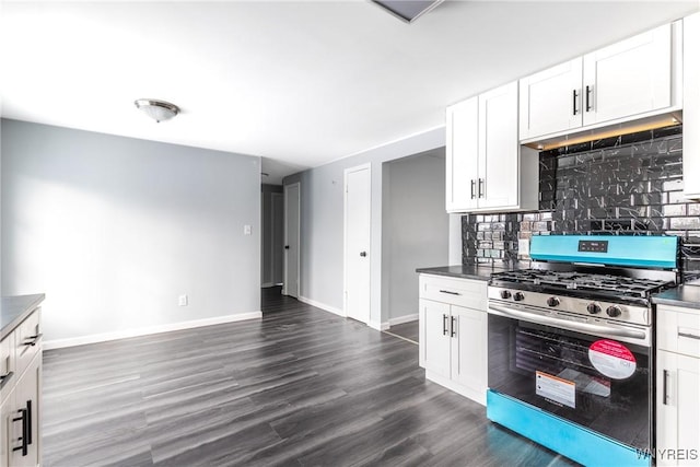 kitchen featuring baseboards, decorative backsplash, gas range, dark wood-type flooring, and white cabinetry