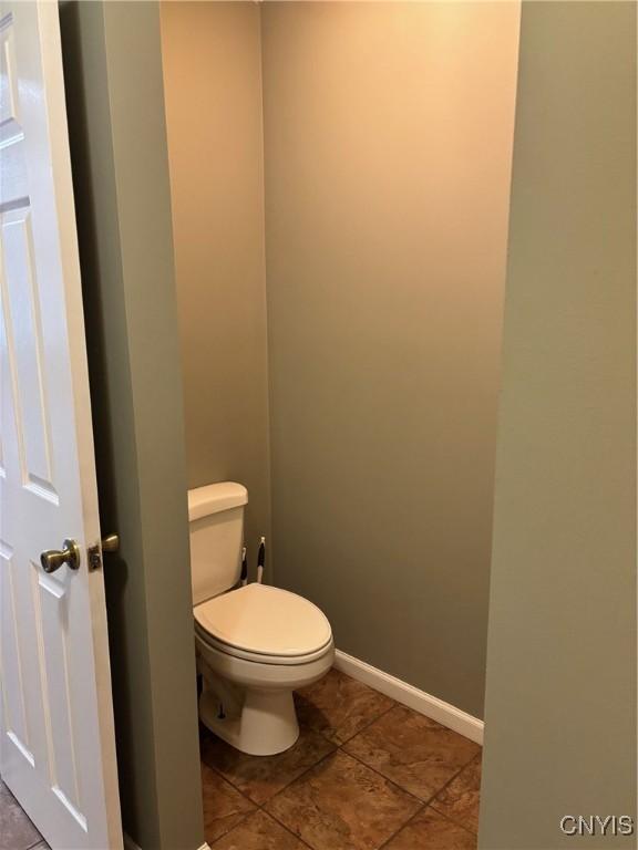 bathroom with tile patterned flooring, baseboards, and toilet