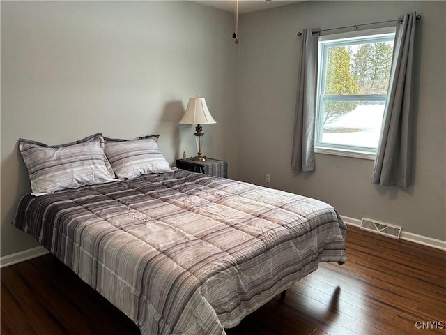 bedroom with wood finished floors, visible vents, and baseboards