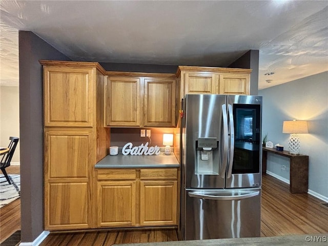 kitchen with dark wood-style floors, stainless steel refrigerator with ice dispenser, and baseboards