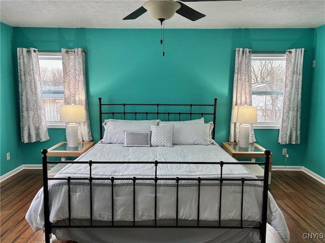 bedroom featuring a textured ceiling, baseboards, and wood finished floors