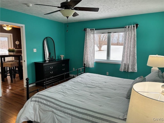 bedroom with baseboards, a textured ceiling, a ceiling fan, and wood finished floors