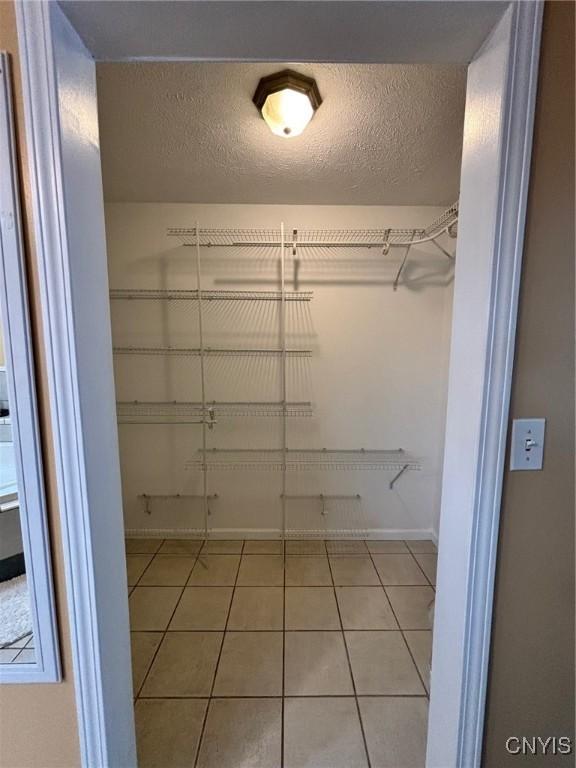 walk in closet with light tile patterned floors