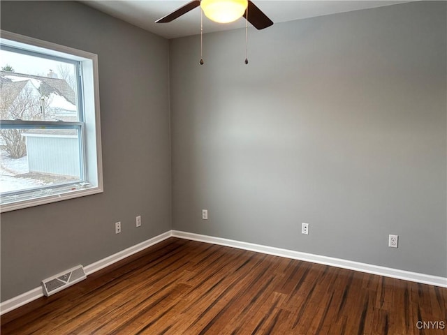 unfurnished room featuring dark wood-type flooring, visible vents, ceiling fan, and baseboards