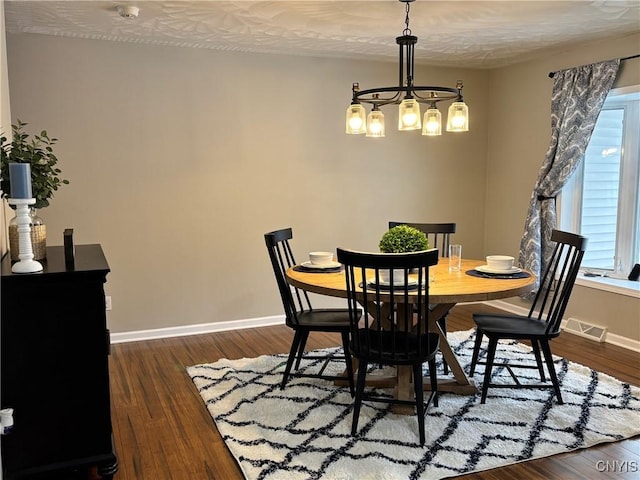 dining room with dark wood-style floors, an inviting chandelier, visible vents, and baseboards