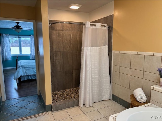 bathroom with tile walls, a ceiling fan, connected bathroom, a tile shower, and tile patterned floors