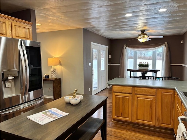 kitchen with dark wood-style flooring, brown cabinetry, stainless steel refrigerator with ice dispenser, and light countertops