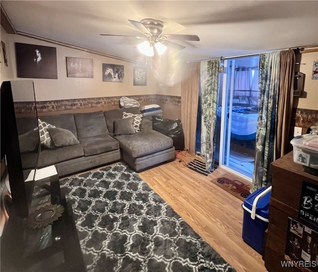 living area featuring a ceiling fan, wainscoting, and wood finished floors