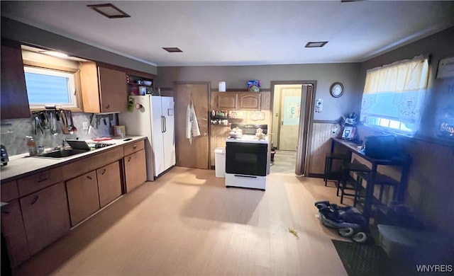 kitchen with white appliances, decorative backsplash, light countertops, light wood-type flooring, and a sink