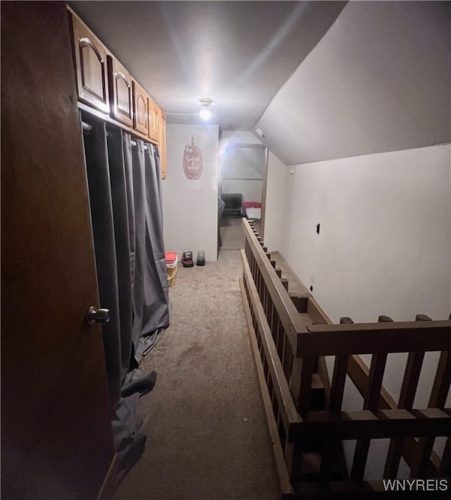 hallway with carpet floors and vaulted ceiling