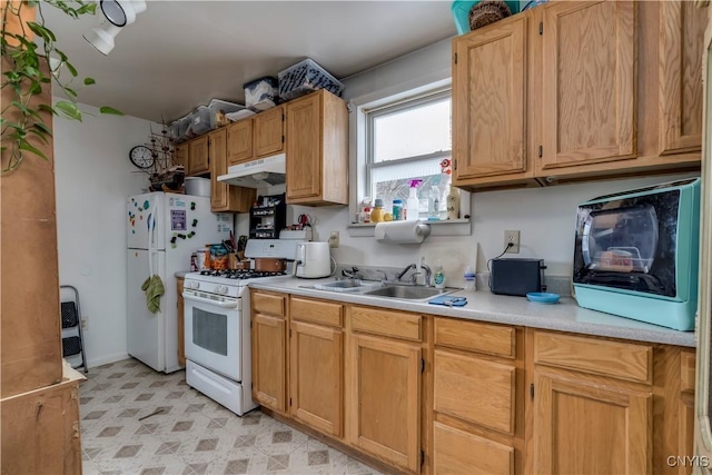 kitchen with under cabinet range hood, white appliances, a sink, light countertops, and light floors