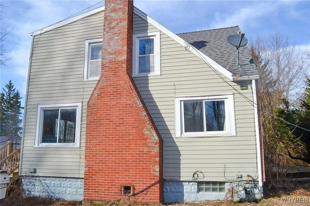 view of home's exterior featuring roof with shingles and a chimney