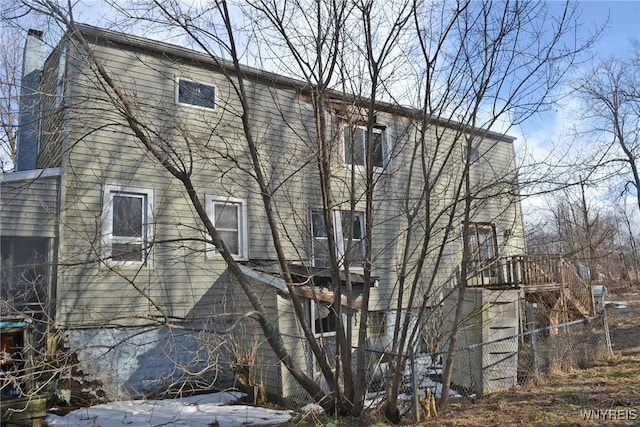 view of side of home with a chimney and fence