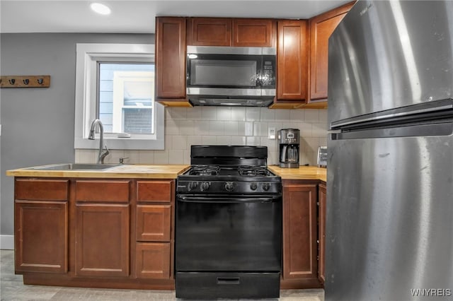 kitchen featuring stainless steel appliances, brown cabinetry, a sink, and decorative backsplash