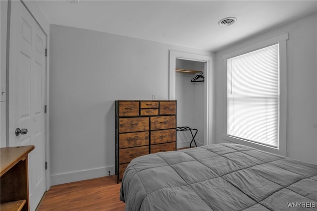 bedroom featuring a closet, wood finished floors, visible vents, and baseboards