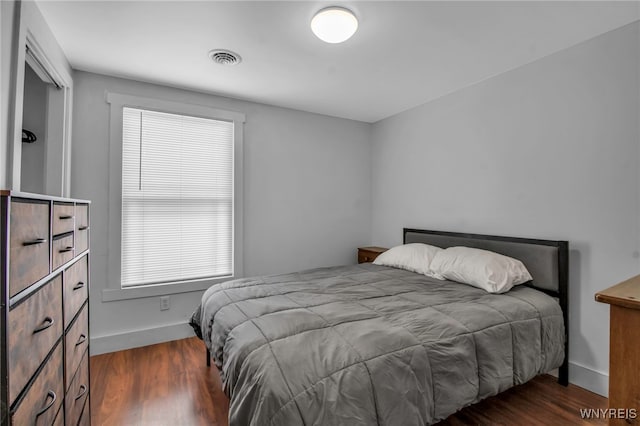 bedroom with dark wood-style floors, visible vents, and baseboards