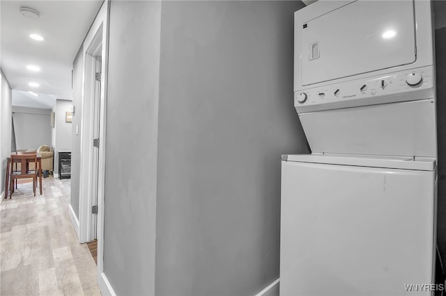 washroom with stacked washer and dryer, recessed lighting, laundry area, and light wood finished floors