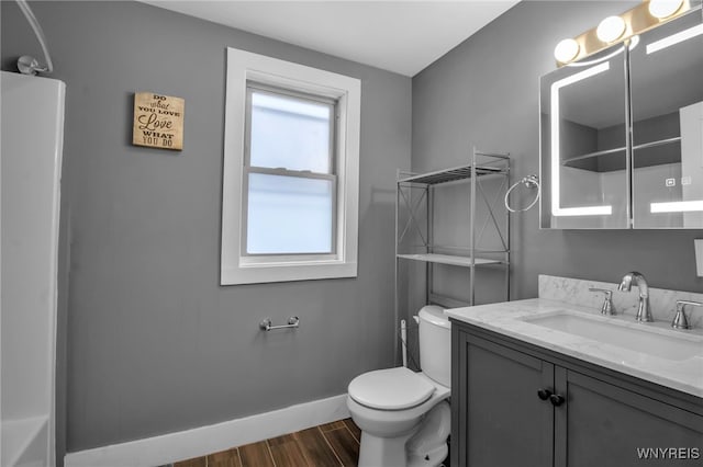 bathroom with vanity, wood finished floors, toilet, and baseboards