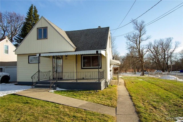 view of front of home with covered porch, a front lawn, and a shingled roof