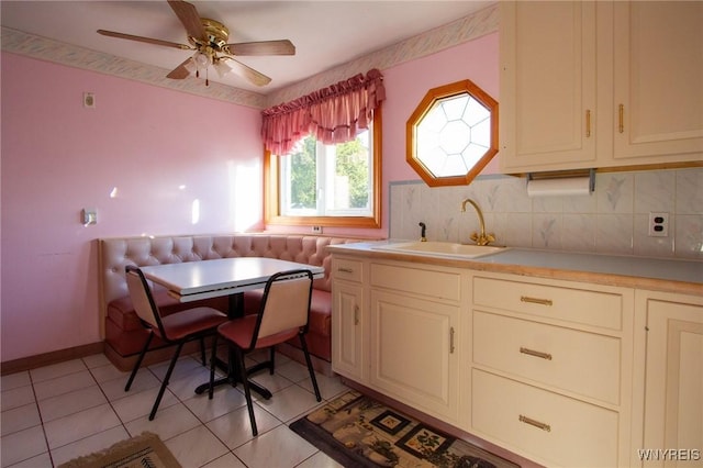 kitchen with light countertops, breakfast area, a sink, and decorative backsplash