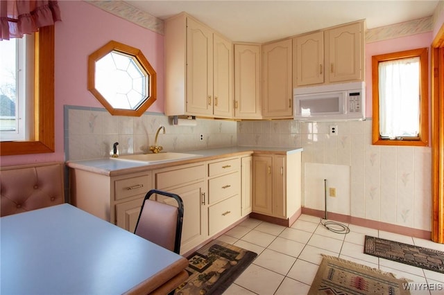 kitchen with light countertops, white microwave, cream cabinets, and a sink