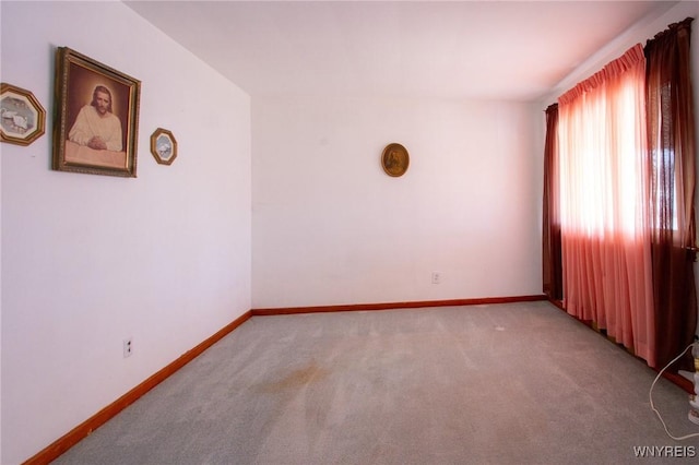 unfurnished room with light carpet and baseboards