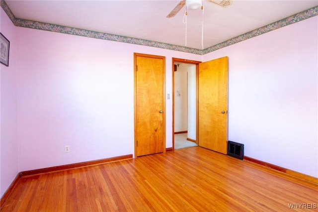 empty room featuring light wood finished floors, visible vents, baseboards, and a ceiling fan