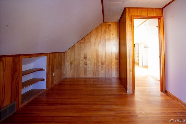 bonus room featuring vaulted ceiling, wood walls, wood finished floors, and visible vents