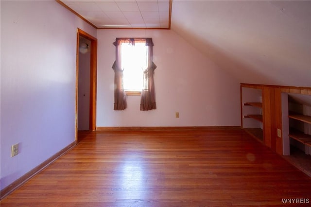 additional living space featuring vaulted ceiling, wood finished floors, and baseboards