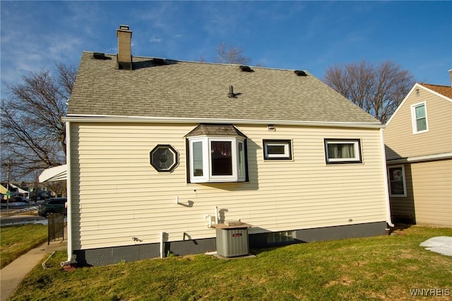 back of house featuring a yard, a shingled roof, and a chimney