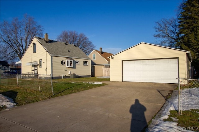 view of front of house featuring a detached garage, an outbuilding, fence, cooling unit, and a front yard