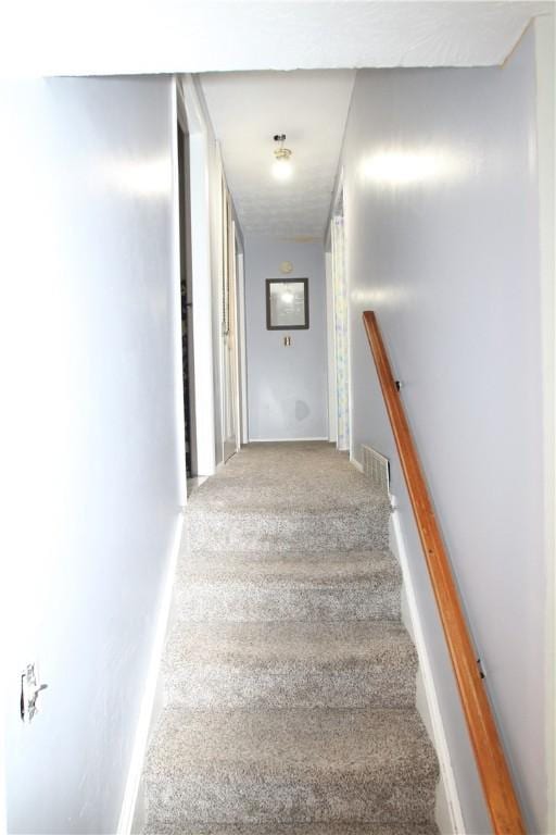 staircase featuring baseboards, visible vents, and carpet flooring