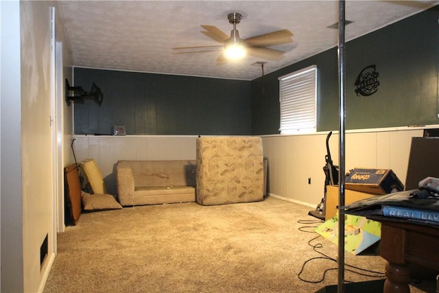 interior space featuring a textured ceiling, wood walls, carpet flooring, and a ceiling fan