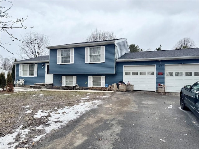 split level home with aphalt driveway and an attached garage