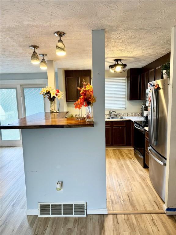 kitchen with visible vents, electric range oven, freestanding refrigerator, light wood-type flooring, and a sink