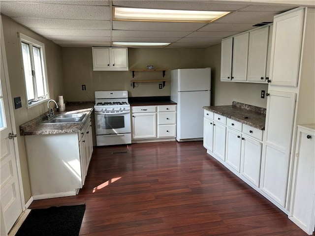 kitchen with white appliances, dark wood finished floors, dark countertops, open shelves, and a sink