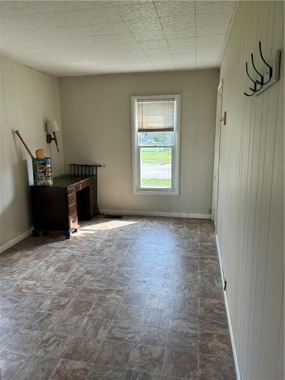 spare room featuring wood walls and baseboards