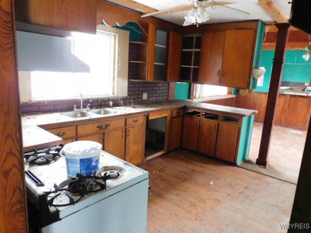 kitchen with decorative backsplash, brown cabinetry, white gas stove, light wood-style floors, and a sink